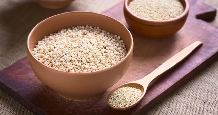 Helle Quinoa-Körner in rustikalen Holzschalen auf natürlichem Holzhintergrund